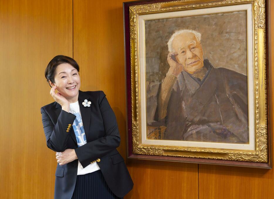 植物学者牧野富太郎の肖像画の前でポーズをとる松坂慶子さん＝13日午後、高知市