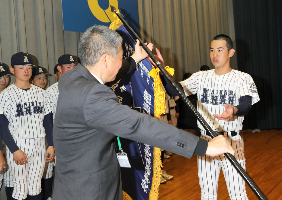 笠原高志校長（中央）からセンバツ旗を受け取る阿南光の井坂琉星主将（右）＝徳島県阿南市の同校で、山本芳博撮影