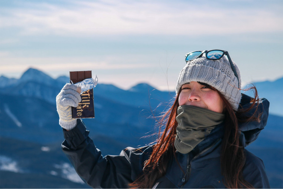 登山の行動食としてチョコレートでカロリー摂取する女性ハイカー