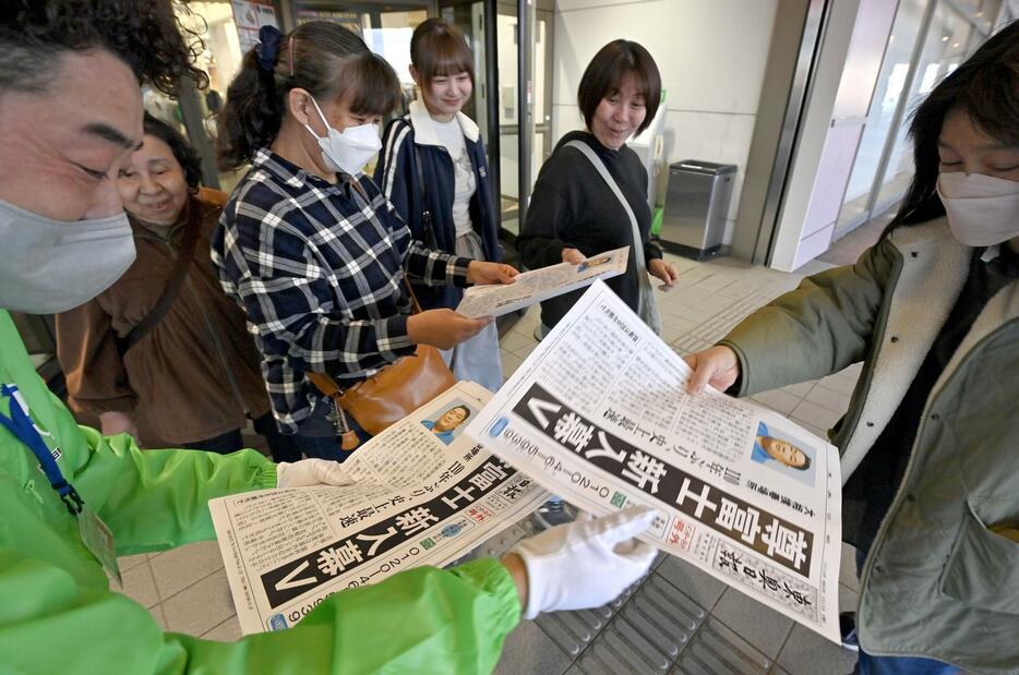 尊富士の優勝を報じる地元紙の号外を手にする人たち＝24日午後、青森県五所川原市