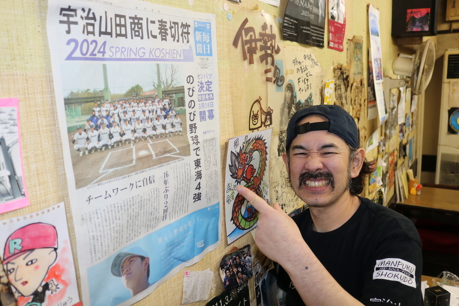 店内に飾られている本紙号外を紹介する店長の鋤柄大平さん＝三重県伊勢市岩渕２のまんぷく食堂で２０２４年３月２３日、原諒馬撮影