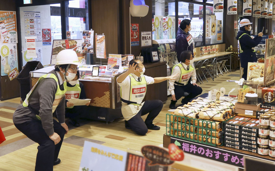 北陸道南条SAで実施した地震防災訓練で、客役を安全な場所へ誘導するテナント従業員ら＝12日午前、福井県南越前町