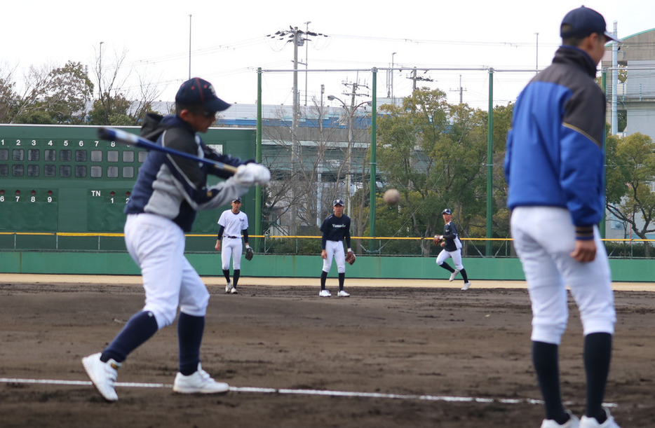 村田治樹監督（左）からノックを受ける宇治山田商の選手＝兵庫県西宮市の鳴尾浜臨海野球場で２０２４年３月２０日、原諒馬撮影