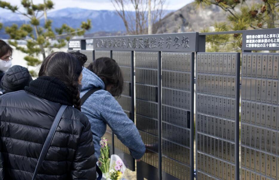 岩手県大船渡市の公園に設置された「芳名板」を見る遺族ら＝11日午後