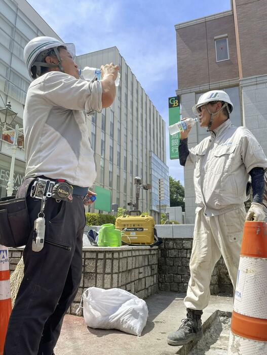 猛暑の日の作業で、スポーツ飲料を飲む道路工事現場の人たち＝2022年6月、前橋市