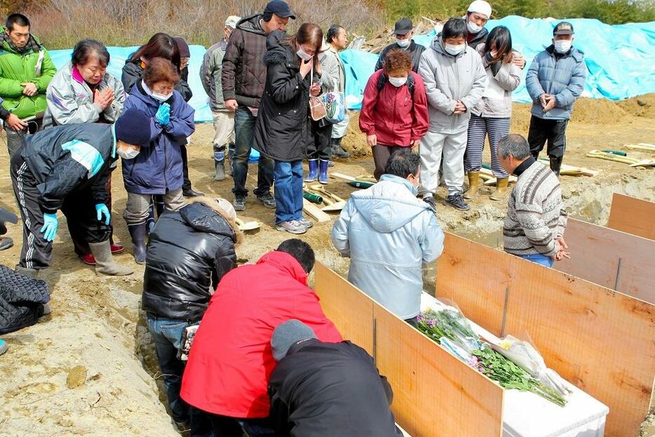 仮埋葬される犠牲者に別れを告げる人たち＝2011年3月22日、宮城県東松島市、長島一浩撮影