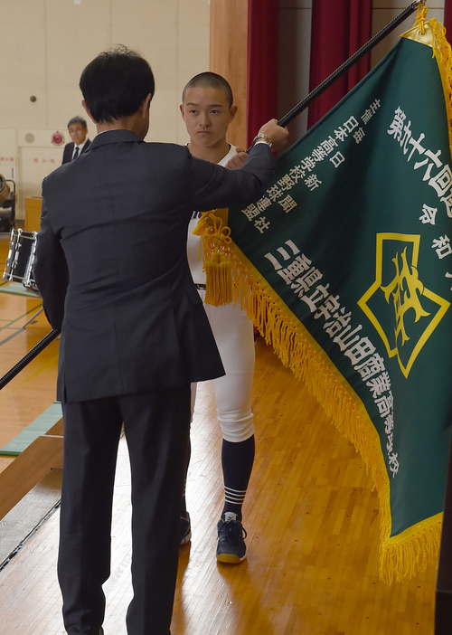 江崎徹校長からセンバツ旗を受け取る伊藤大惺主将＝三重県伊勢市の宇治山田商で２０２４年３月６日、大竹禎之撮影