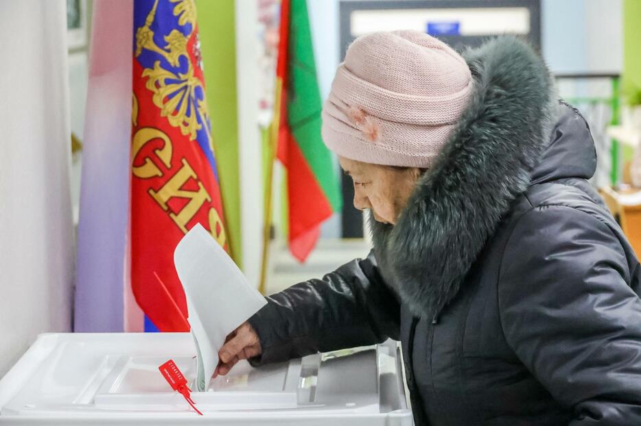 16日、ロシアが実効支配するウクライナ南部ザポロジエ州メリトポリで、ロシア大統領選の投票をする女性（タス＝共同）