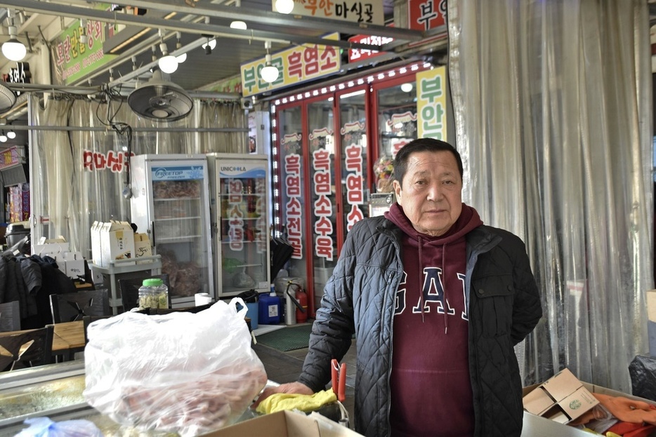 韓国・城南で営む食肉店の前に立つ金容北さん＝2024年1月（共同）