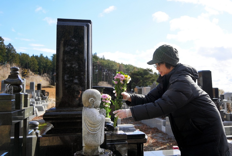 行方不明の女子部員のお墓に花を供える畠山由紀子さん＝2023年12月、岩手県陸前高田市、三浦英之撮影