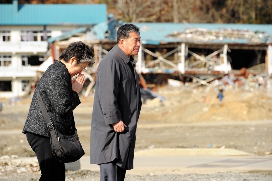 地震発生時刻に合わせ、高田高校前で黙禱（もくとう）する小野寺素子さんの父・毛利奉信さん（右）と母・みどりさん＝2012年3月11日、岩手県陸前高田市、森井英二郎撮影