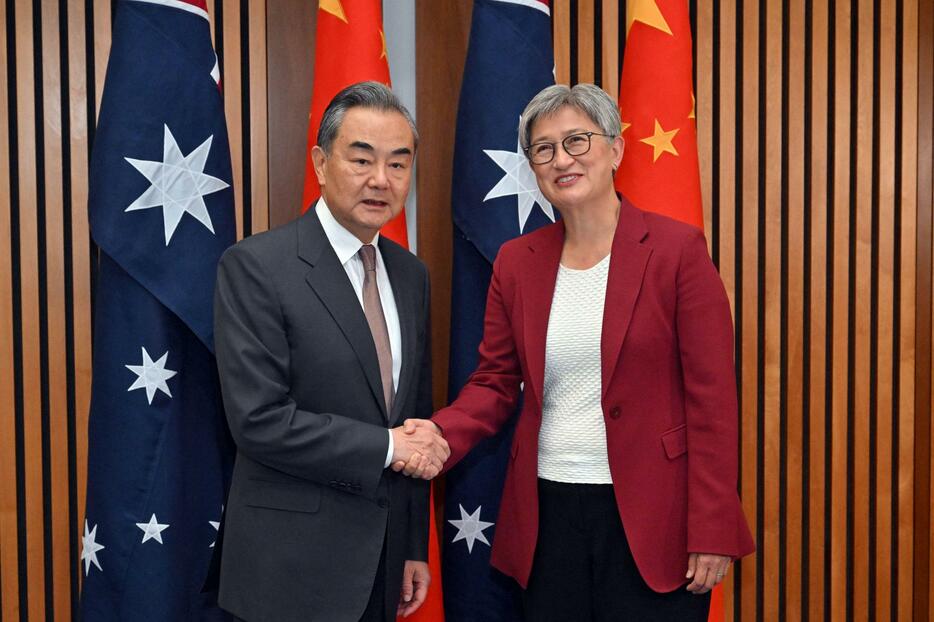 会談する中国の王毅外相（左）とオーストラリアのウォン外相＝20日、キャンベラ（ロイター＝共同）