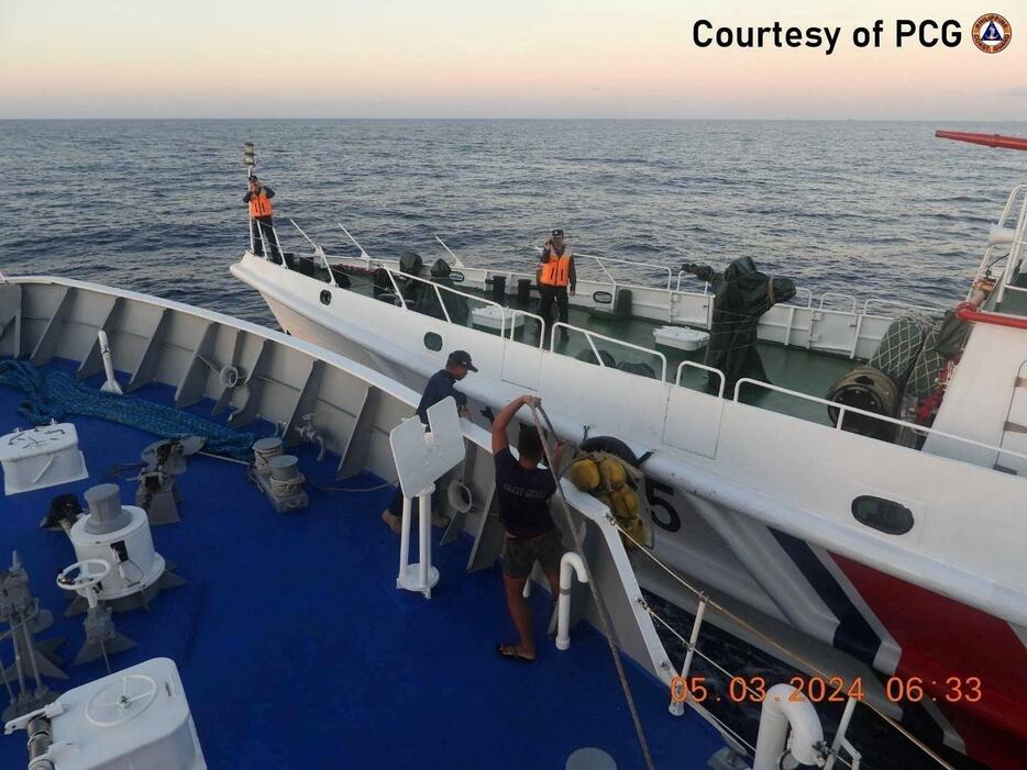 5日、南シナ海で船体を調べるフィリピン沿岸警備隊（沿岸警備隊提供・ロイター＝共同）