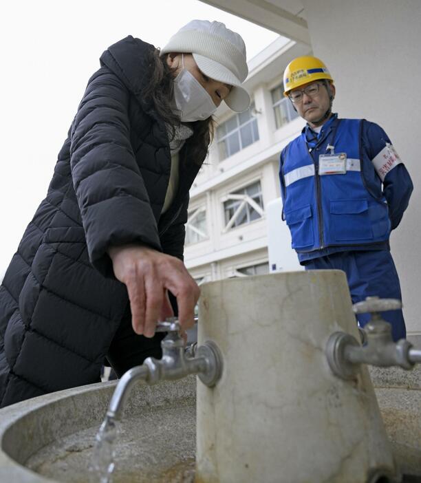 避難生活を送る石川県珠洲市立上戸小の水が使えるようになり、蛇口をひねる藤部富子さん＝10日午前