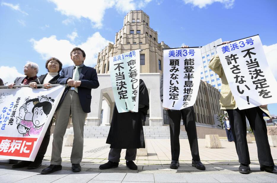 関西電力美浜原発3号機と、高浜原発1～4号機の運転差し止めを認めない福井地裁の決定を受け、地裁前で「不当決定を許さない！」などと書かれた垂れ幕を掲げる住民ら＝29日午後1時7分