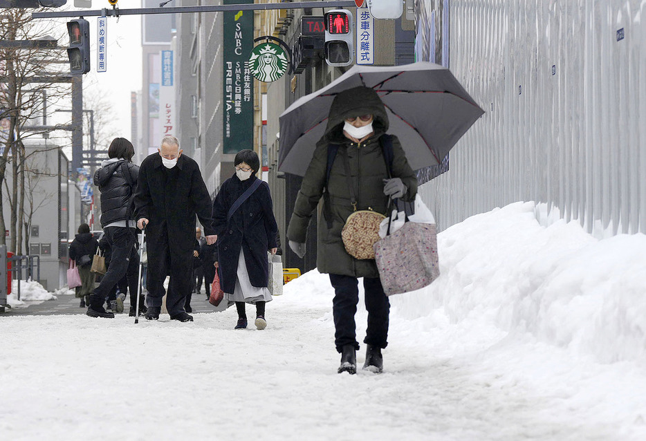 札幌市内で雪道を歩く人たち＝12日午後