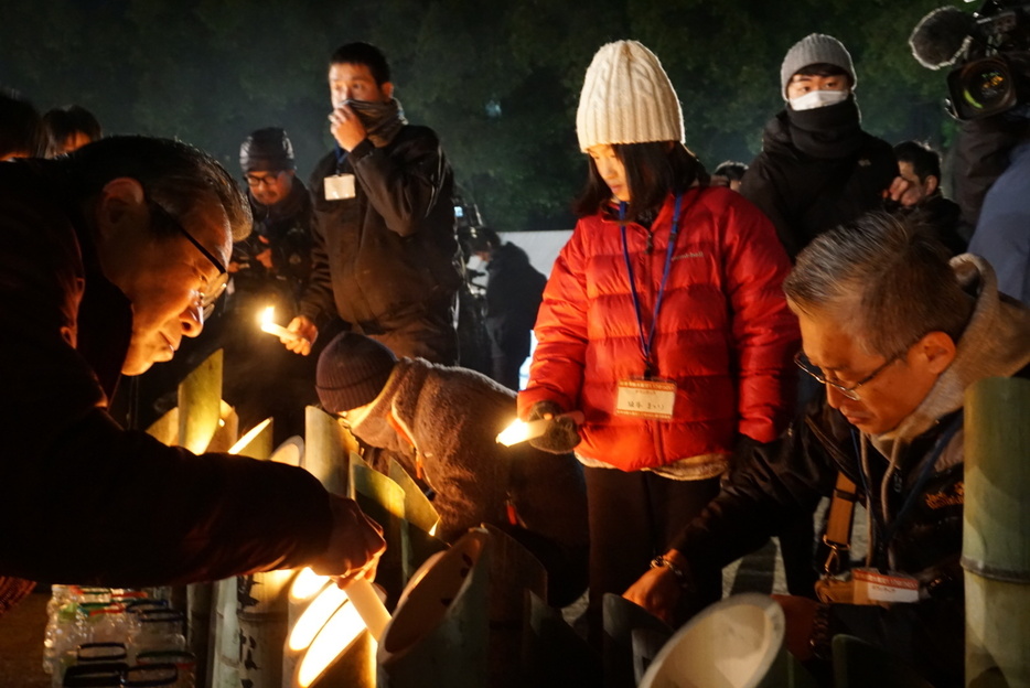 ［写真］子供たちも竹燈籠に火を灯した＝17日午前5時半ごろ、神戸市中央区で