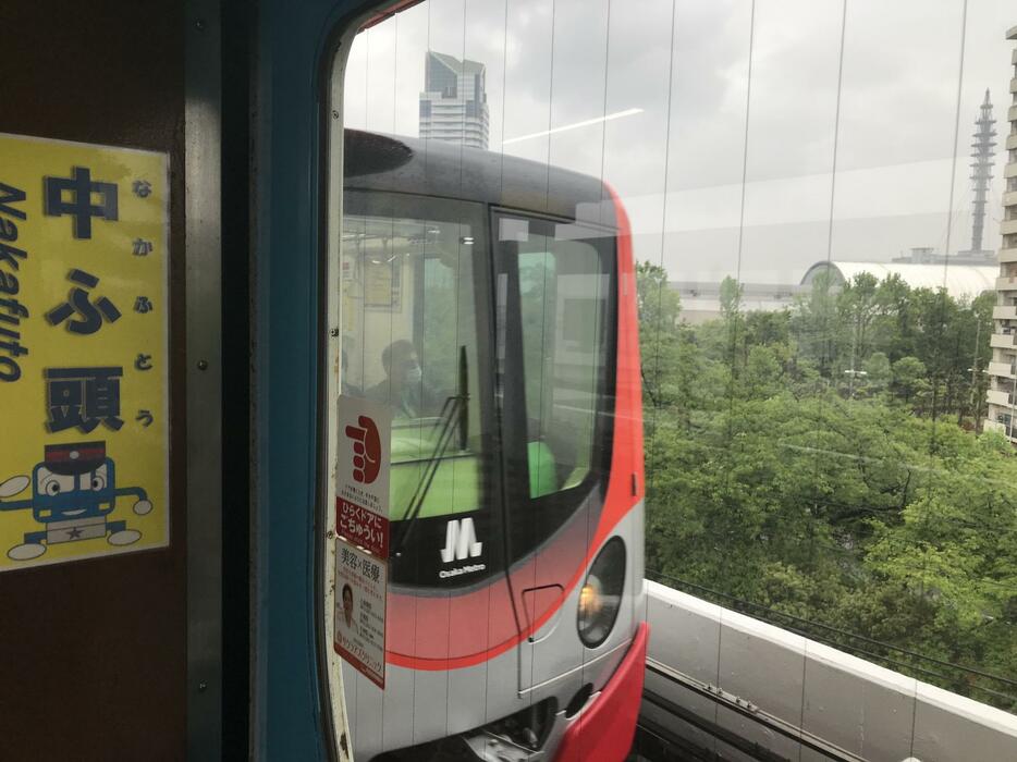 ［写真］中ふ頭駅はインテックス大阪（写真右側の白い屋根）の最寄り駅。写真中央はニュートラムの車両＝28日午前、大阪市住之江区で