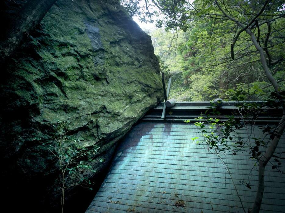 沖津宮の御屋根に寄りかかる巨岩。島内に散在する巨岩の中には古代祭祀の磐座として使われたものもある。写真／藤原新也