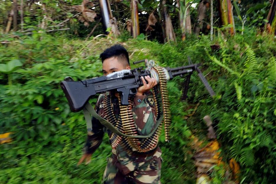 [写真]マラウィでの戦闘でマシンガンを手に移動するフィリピン政府軍の兵士（ロイター/アフロ、2017年6月28日撮影）