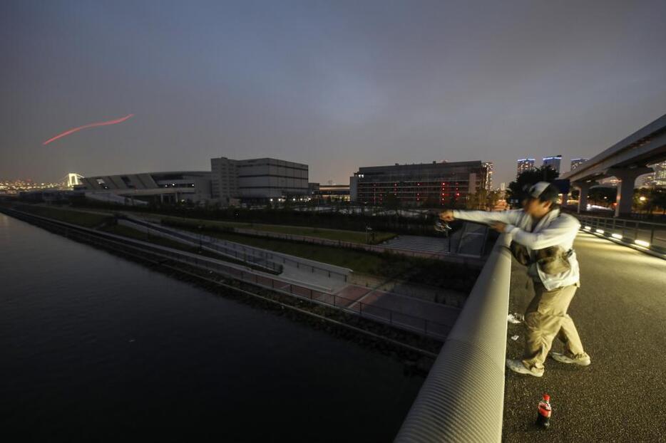 [写真]豊洲市場をバックに、市場前の海にキャストするH君＝東京都江東区、環状2号線有明北橋