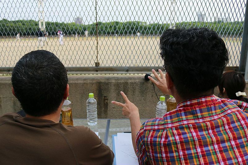 [写真]草野球チーム協力のもと、三代澤アナが実況を行う。右は伊藤史隆アナ。伊藤アナも新人時代はこのように草野球で実況の練習を行ったという=大阪市中央区で（撮影：柳曽文隆）