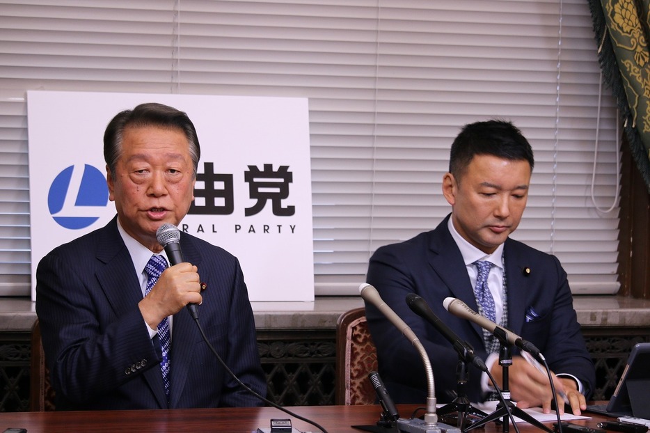 [写真]会見する小沢代表（左）と山本代表