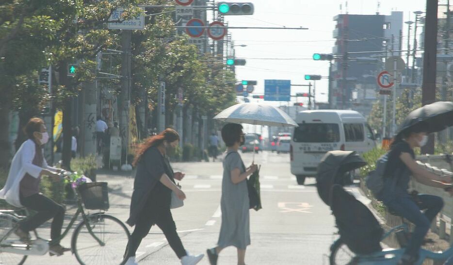 [写真]強い西日を受け日傘をさす人も多かった＝1日午後4時20分ごろ、大阪市阿倍野区で