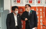 「イエイ」と言いながら岡田専門監（左）に肘タッチする三村知事＝5月26日