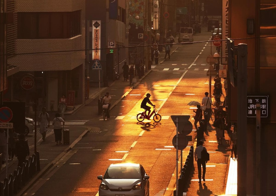 夕日が差すビル街の道路を行き交う人たち