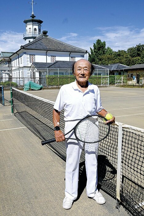 60年通うテニスコートでラケットを持ち笑顔を見せる岡田さん