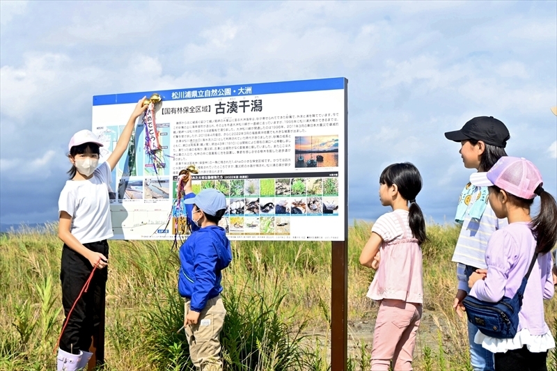 干潟付近に設置された看板と完成を祝う子どもたち