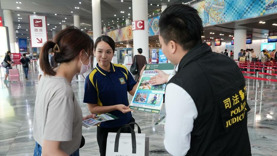 マカオ国際空港利用客へ機内窃盗被害予防を呼びかける警察官（写真：マカオ司法警察局）