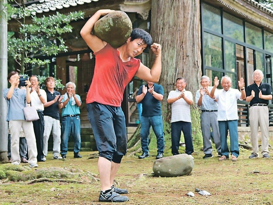 地元住民の前で１３２キロの石を持ち上げる西野さん