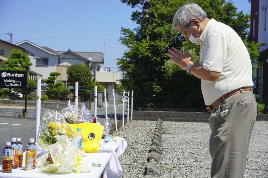 園の駐車場に設置された献花台で手を合わせる男性＝5日午前、静岡県牧之原市