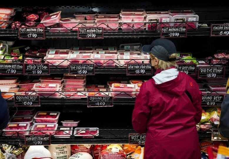 食料品店で肉を選ぶ女性客。