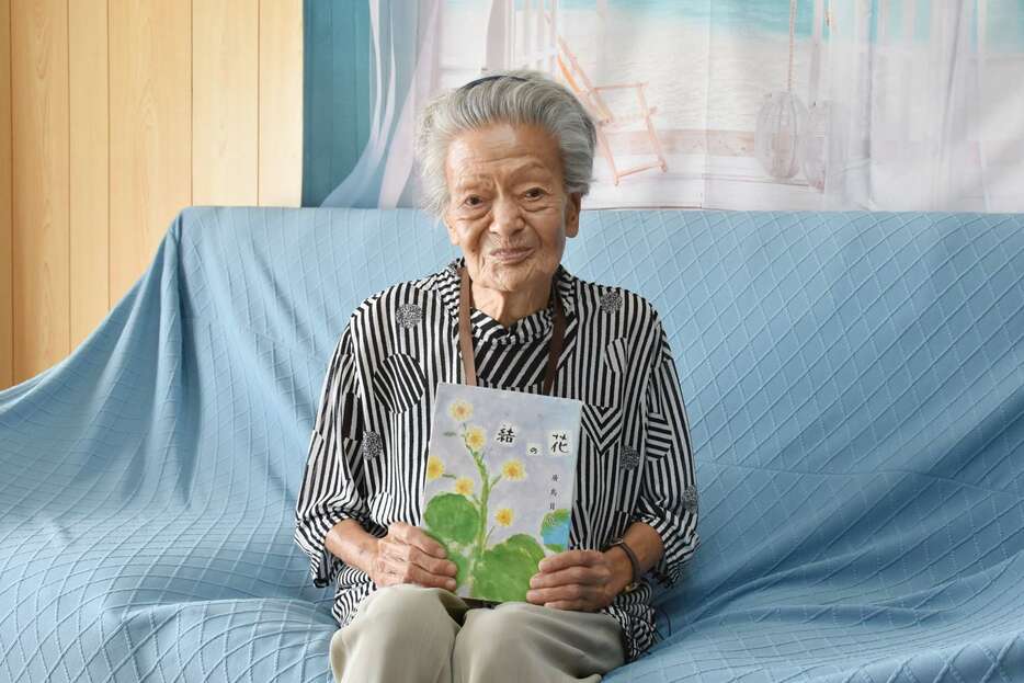 作品集「結の花」を手にする廣島員代さん＝伊仙町木之香