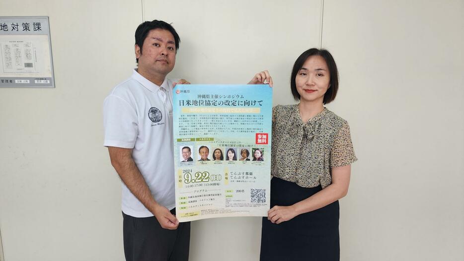 シンポジウムへの来場を呼び掛ける県基地対策課の大城美千代副参事（右）と友寄言主査＝県庁