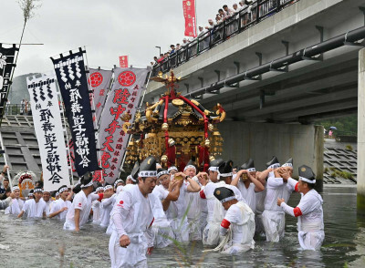 雨が降る中、力強く大槌川を渡るみこしの担ぎ手