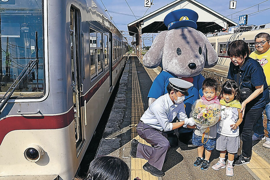 出発式で運転士に花束を贈る園児＝電鉄黒部駅