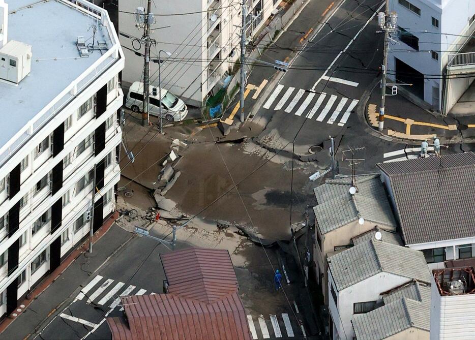 陥没した市道交差点。周囲の住宅も傾いた（26日午前11時18分、広島市西区）