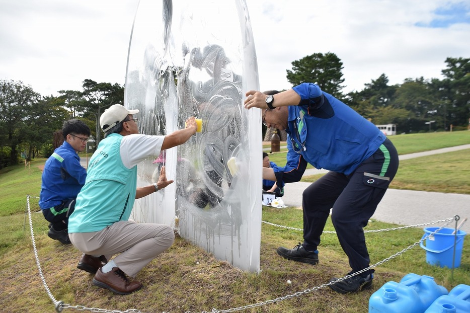 彫刻「ディスタンス」を磨く参加者たち（常盤公園の彫刻の丘で）