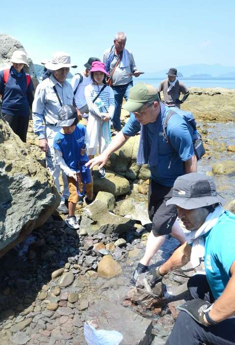 獅子島の発掘調査現場で見学者に説明する中島保寿准教授（右）と筆者（右から２人目）＝鹿児島県長島町