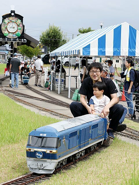 ミニ列車に乗って風を浴びながら走る親子