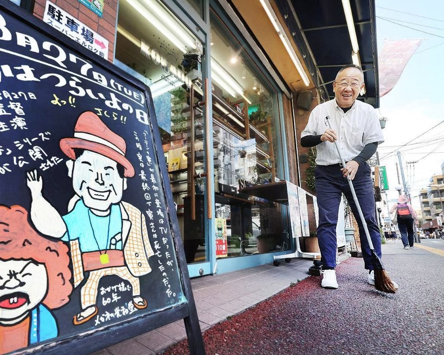 日替わりで描く店先の掲示板のそばで笑顔を見せる大島さん