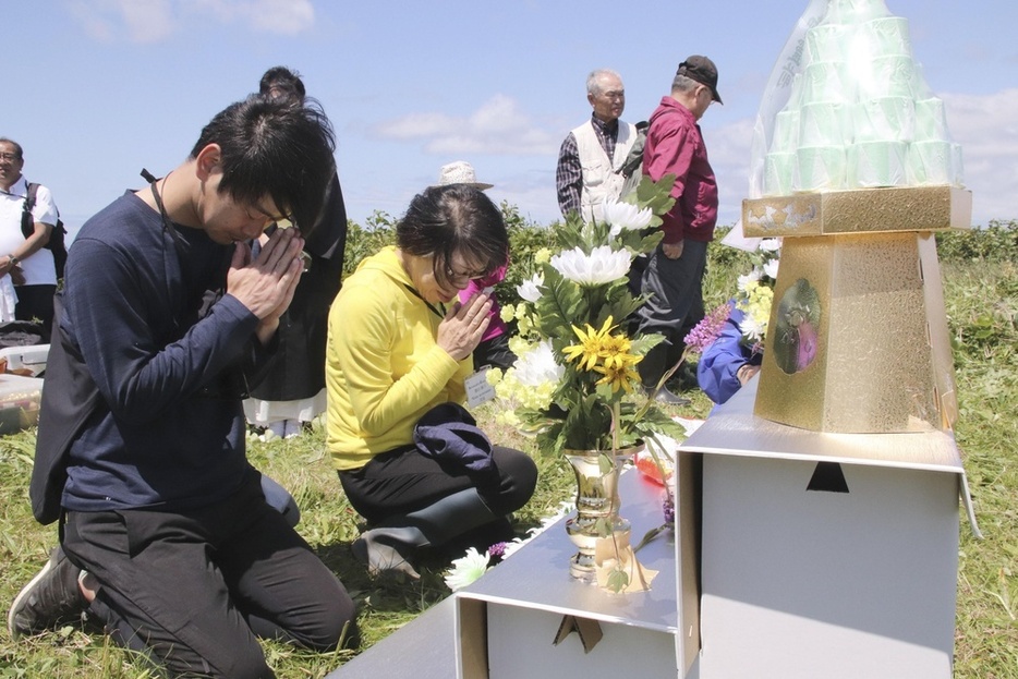 北方領土・択捉島のペケンリタ墓地での慰霊式で手を合わせる墓参団員＝2019年7月