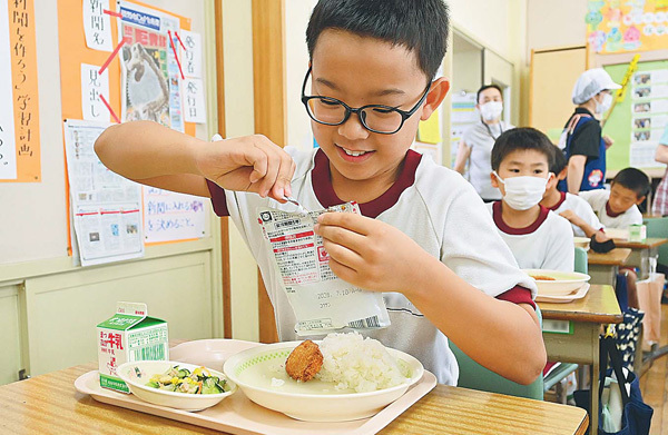 レトルトパウチを開ける児童。カレーに笑みがこぼれる（福島県南相馬市で）