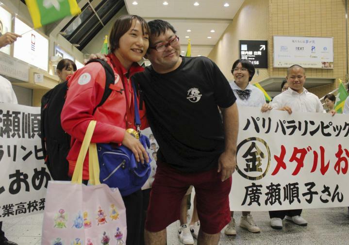 横断幕の前で笑顔を見せる広瀬順子選手（左）と夫の悠さん＝12日夜、松山空港