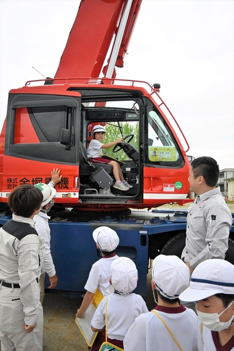 重機の運転席に試乗し、笑顔を見せる児童