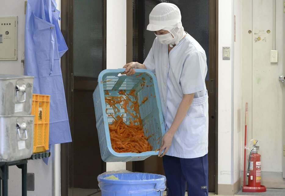 調理で出た野菜くずを捨てる喜入学校給食センター職員＝鹿児島市喜入町